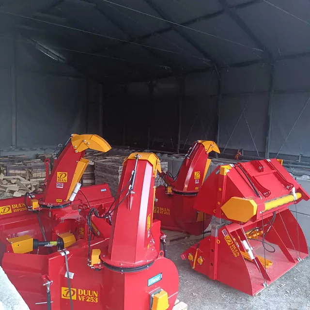 Flere Duun snøfresere og redskaper lagret under telt med grusdekke.