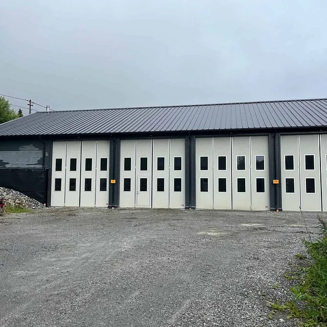 Verkstedbygg med flere store garasjeporter og gruslagt forplass.